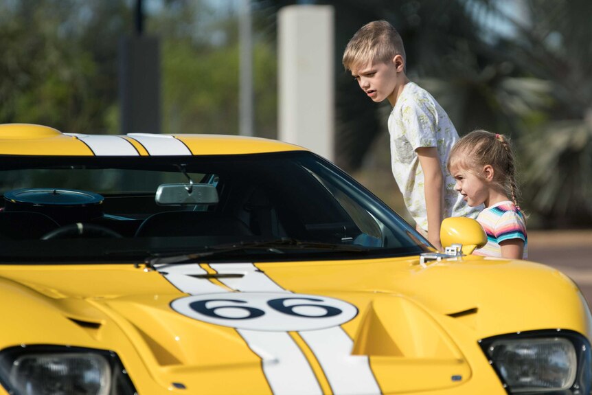 Children check out a yellow vintage car