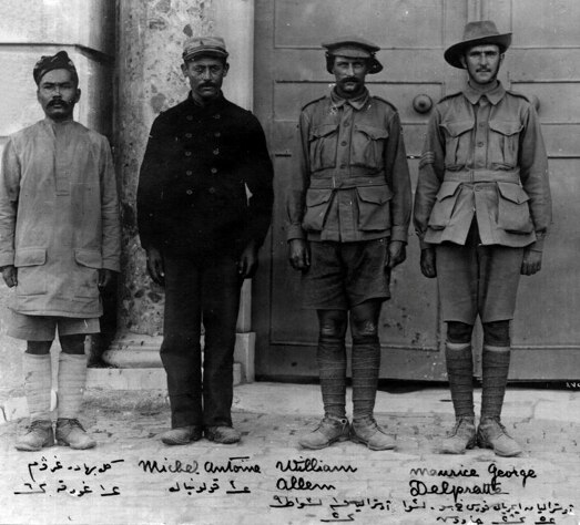 A blakc and white photo of four prisoners of war standing side by side.  