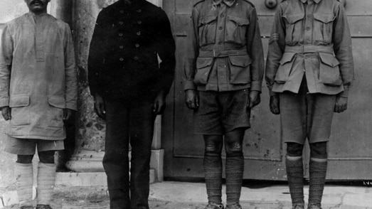 A blakc and white photo of four prisoners of war standing side by side.  