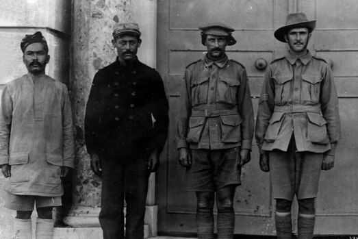 A blakc and white photo of four prisoners of war standing side by side.  
