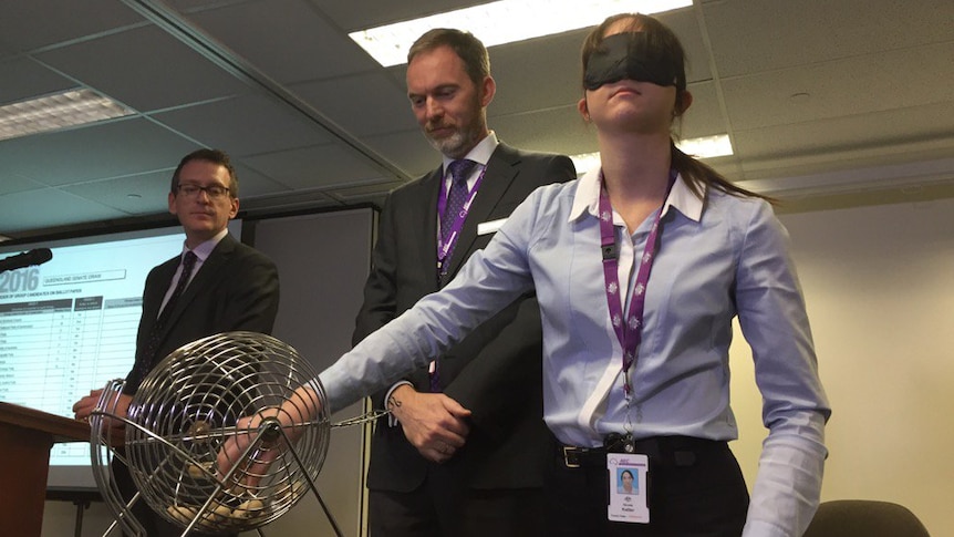 A blindfolded AEC employee picks numbered balls