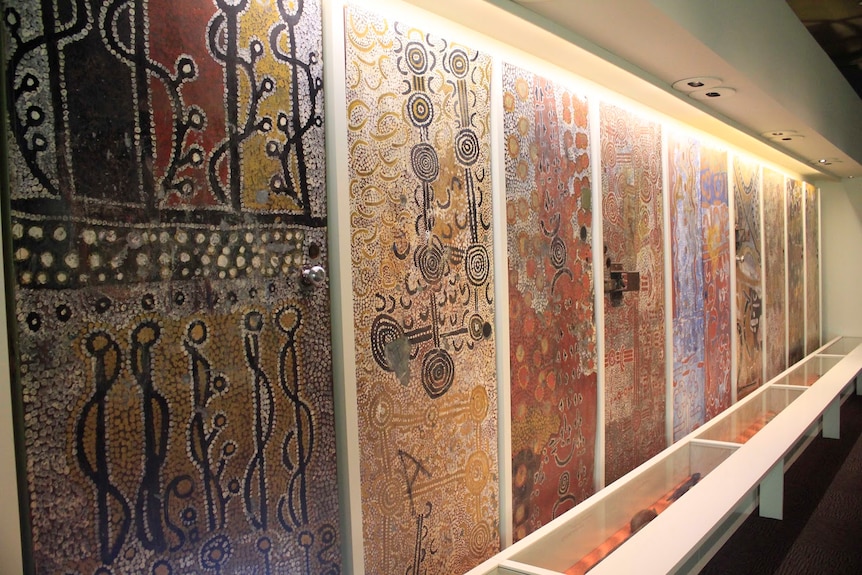 A series of nine doors painted with intricate Aboriginal designs, in a line along a gallery wall