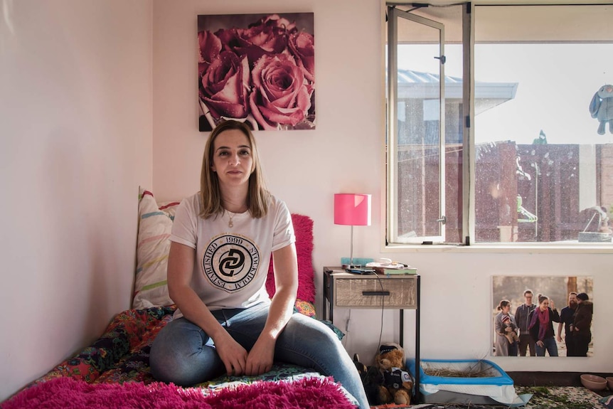 A woman sitting on her bed looking serious