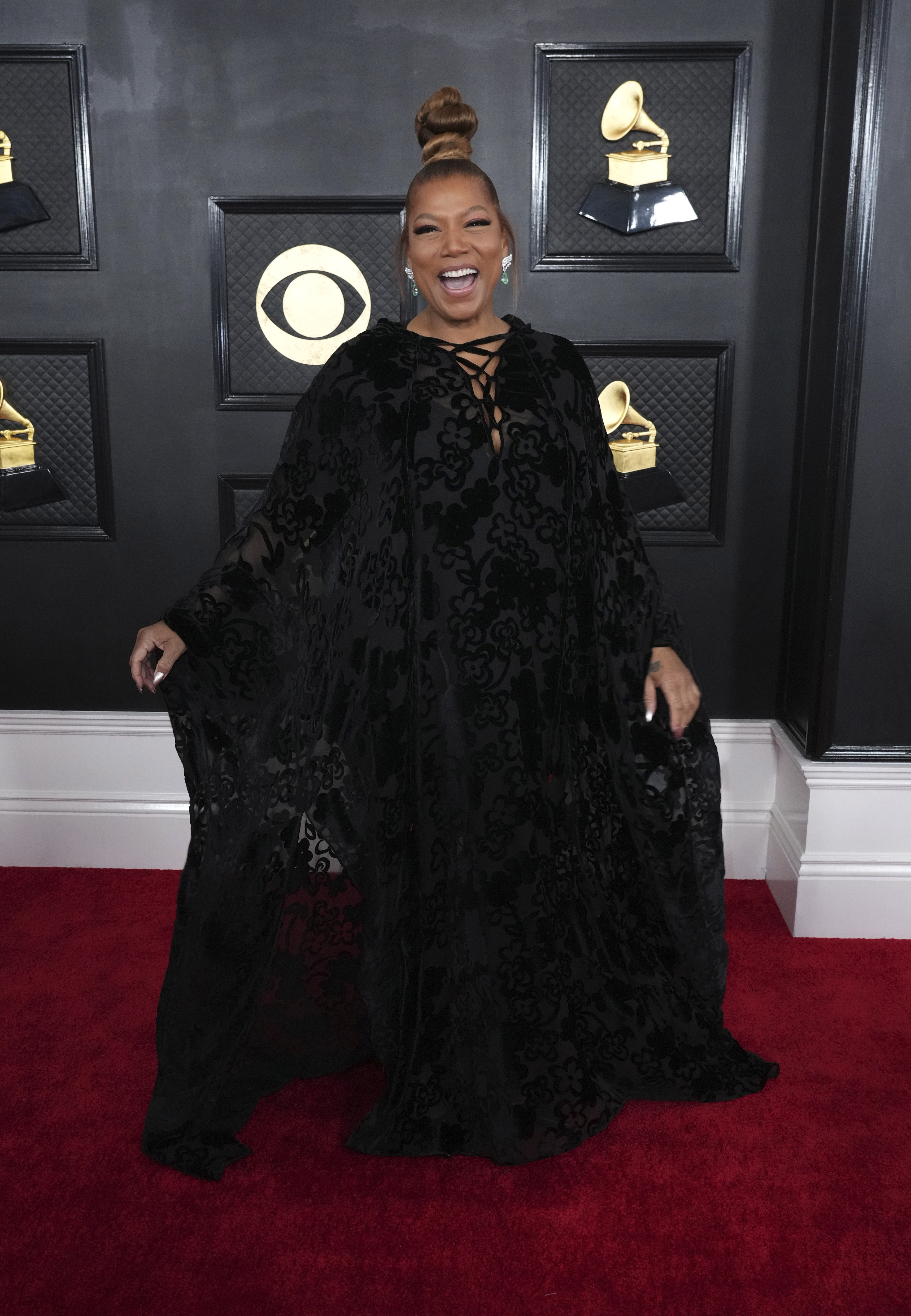 Queen Latifah wearing a long-sleeved black dress with chris-cross ties at the front. 