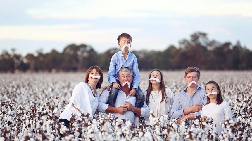 A family of six standing in a cotton field wearing fake cotton moustaches