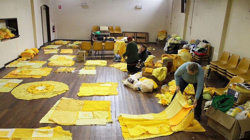 Holbrook: Volunteers layout yellow knitted patches for the yellow submarine yarn bombing project