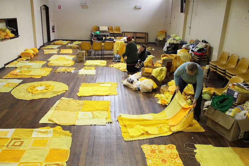 Holbrook: Volunteers layout yellow knitted patches for the yellow submarine yarn bombing project