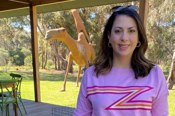 Deema Audeh standing in front of a statue of a camel wearing pink