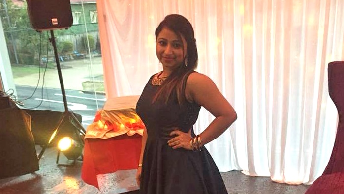 Ravneet Kaur stands wearing a black dress.