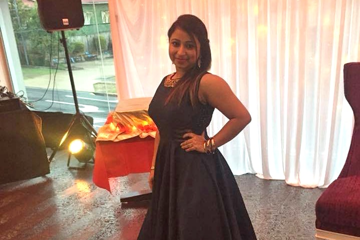 Ravneet Kaur stands wearing a black dress.