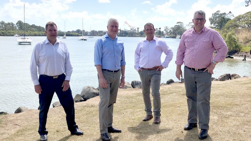 Four men stand on the banks of the Burnett River in Bundaberg.