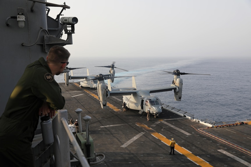 Un marine américain observe les avions MV-22 Osprey après leur atterrissage sur le pont.