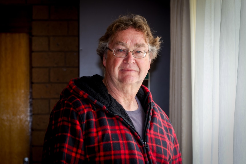 A man wearing a red and black checked button up shirt.