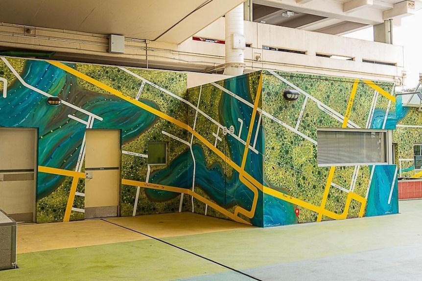 blue, green and yellow mural on a multi-faceted wall in an underground passageway