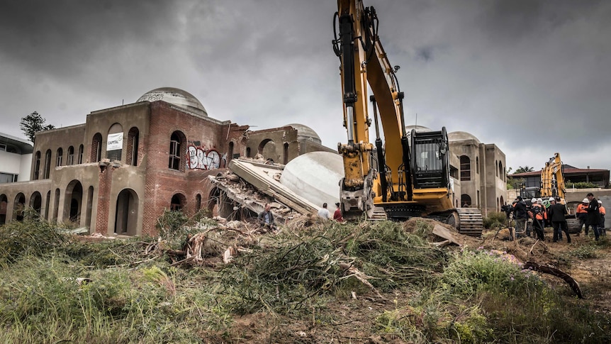 An excavator sits in front of the partially demolished palace known as the Taj on Swan.