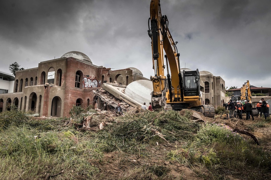 An excavator sits in front of the partially demolished palace known as the Taj on Swan.