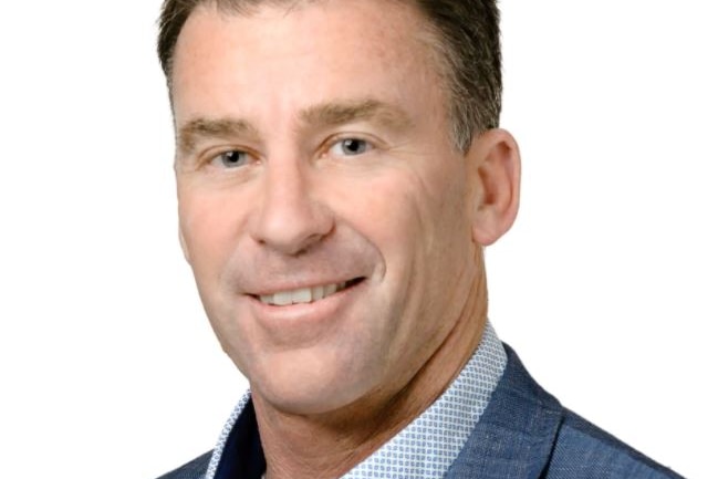 A close-up headshot of a middle-aged man wearing a pal blue suit