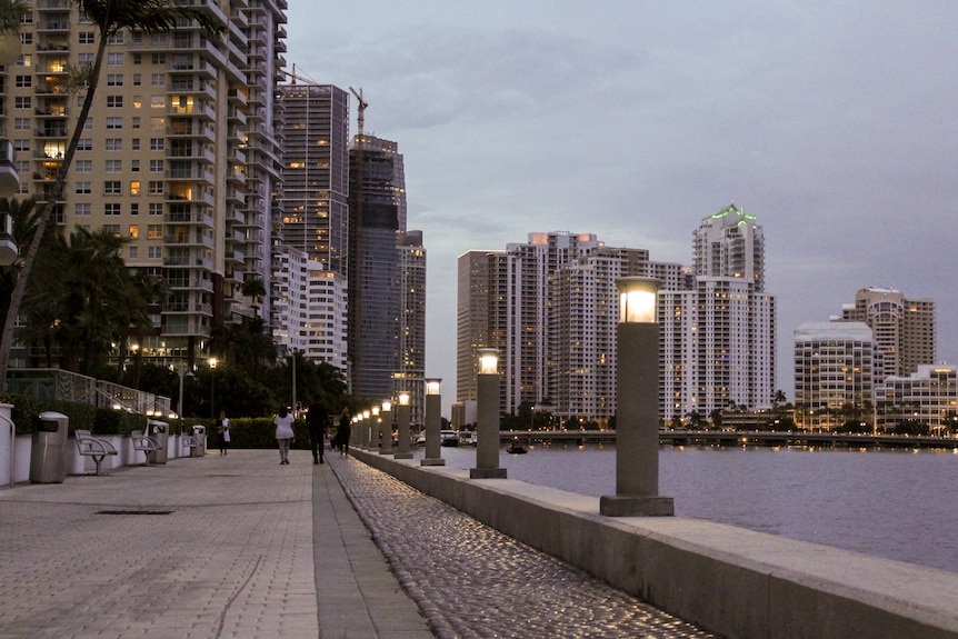 A concrete path provides a short space between skyscrapers and the open ocean