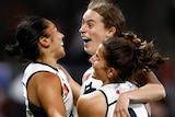 Three Carlton AFLW players embrace as they celebrate a goal against the Western Bulldogs.