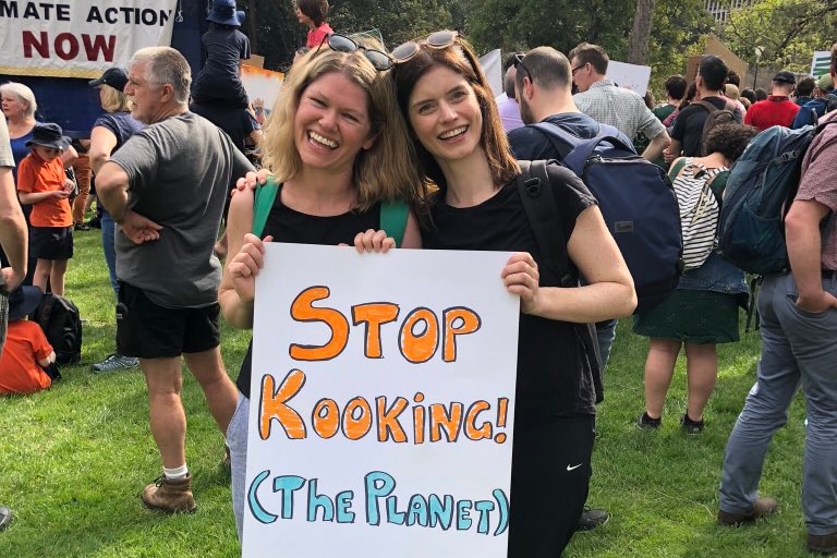 Kate McLennan and Kate McCartney pose with a "Stop Kooking! (the Planet)" sign at Melbourne's Climate Strike in 2019)