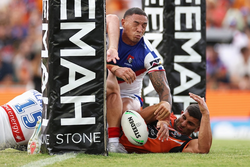 A man drops the ball over the line during a rugby league match