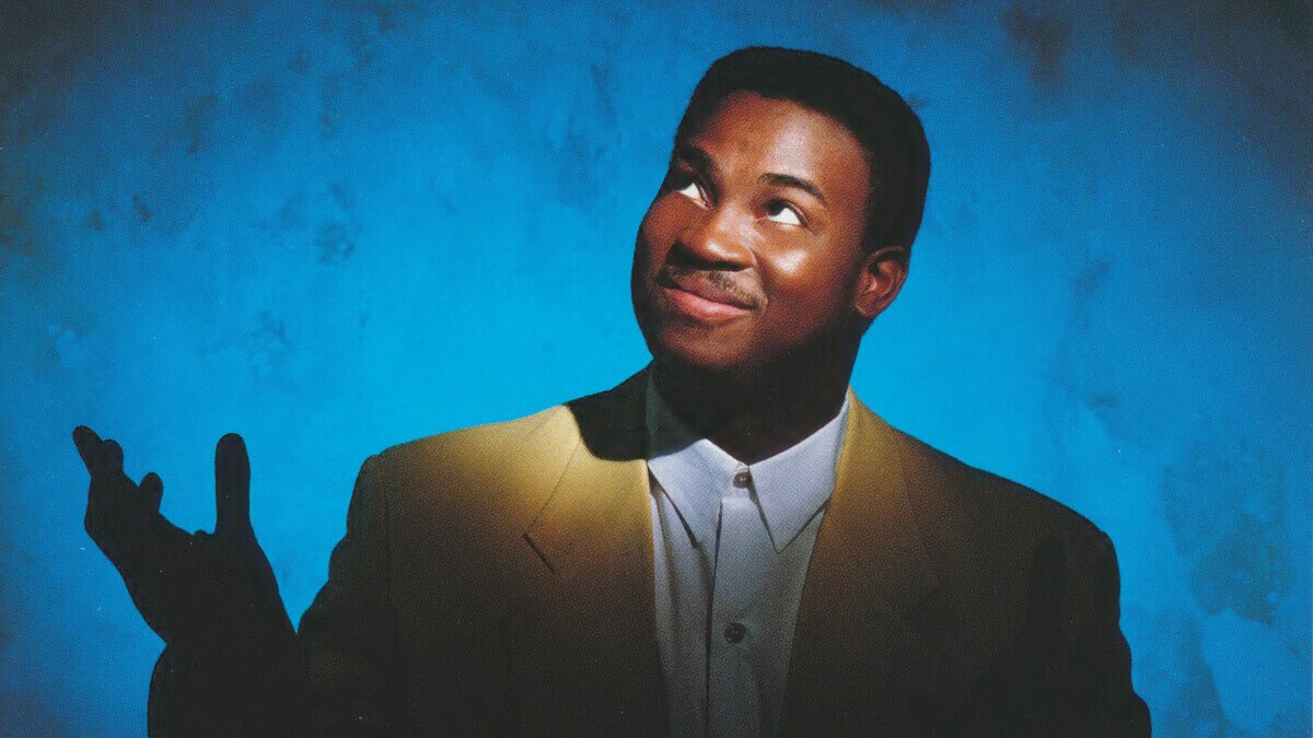 A photo of a young Russell Malone standing in front of a blue backdrop