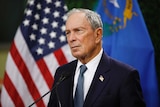 US billionaire Michael Bloomberg stands in front of an American flag.