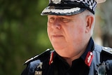 A close-up of the face a man in a NT Police uniform, walking outside on a sunny day.