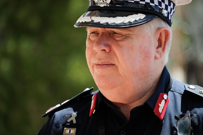 A close-up of the face a man in a NT Police uniform, walking outside on a sunny day.