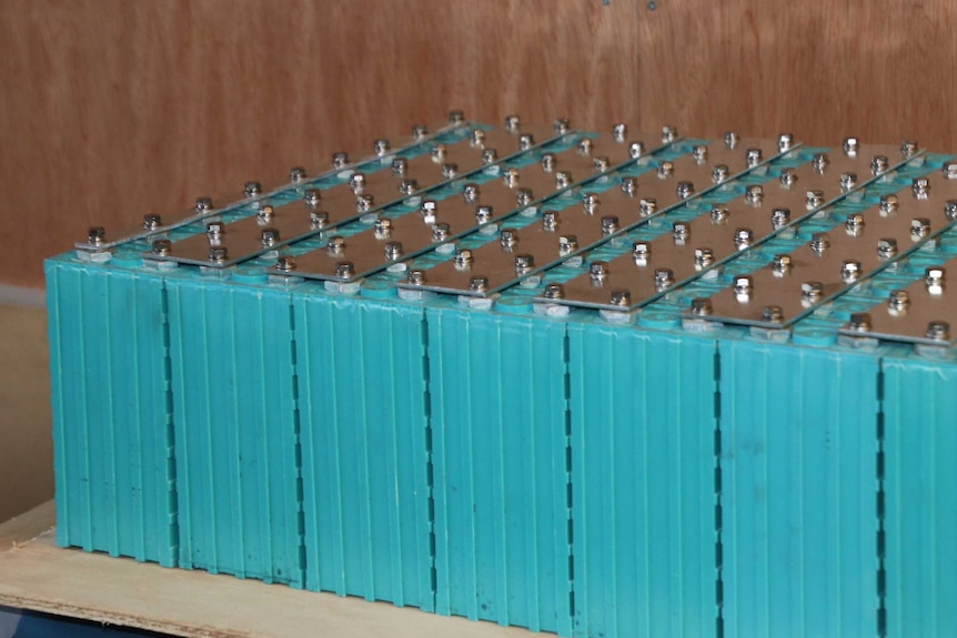 A row of recycled lithium ion batteries in a bright teal casing sit on a table.