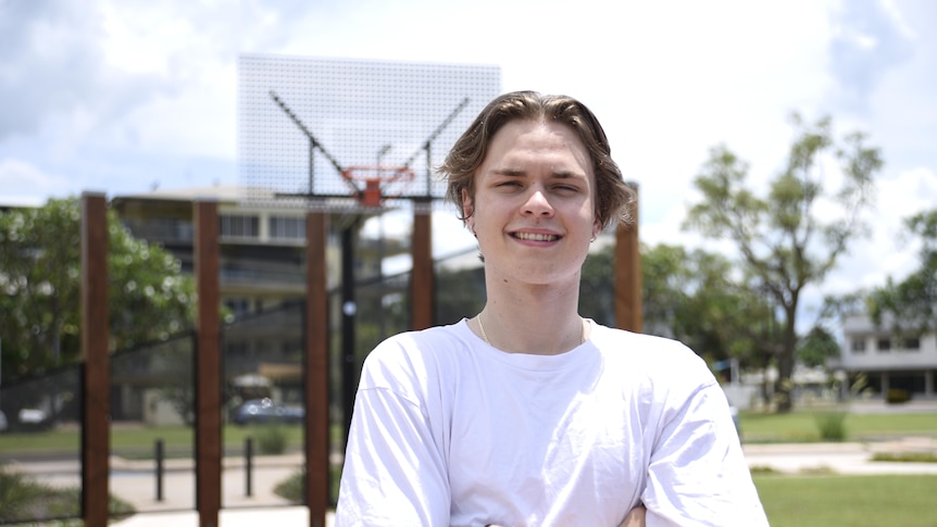 A young boy stands in front of a basketball hoop. 