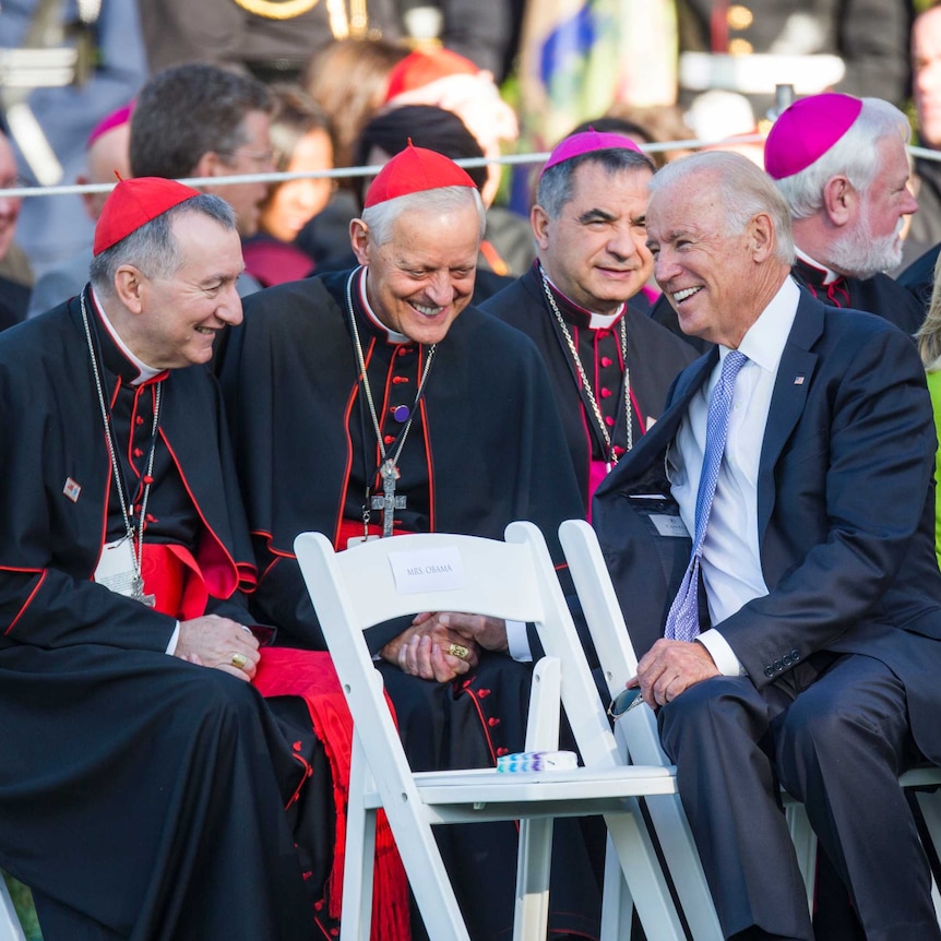 President Joe Biden speaks with cardinals from the Catholic Church during a ceremony.