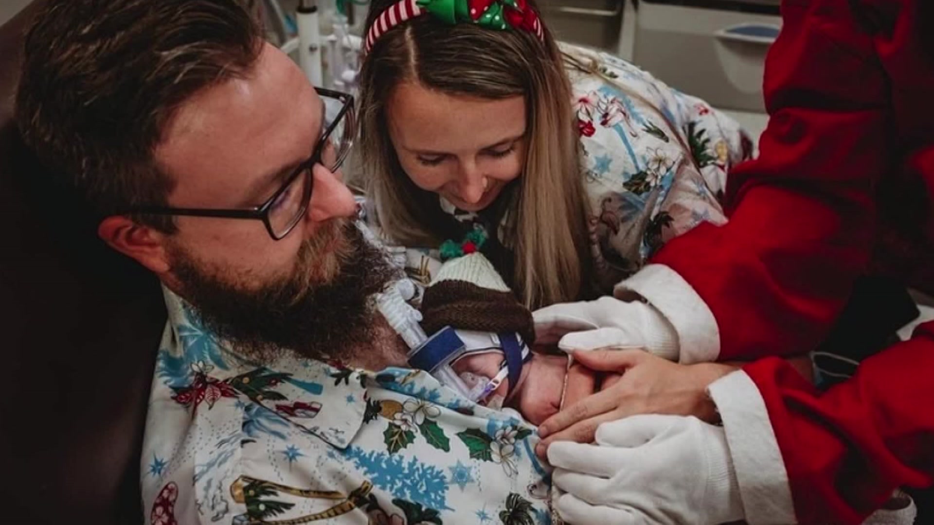 Nathan and Sophie Streeter wear Christmassy clothes in a hospital with Charlie laying on Nathan's chest.