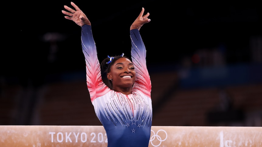 Woman smiling after nailing her balance beam routine at the Olympics