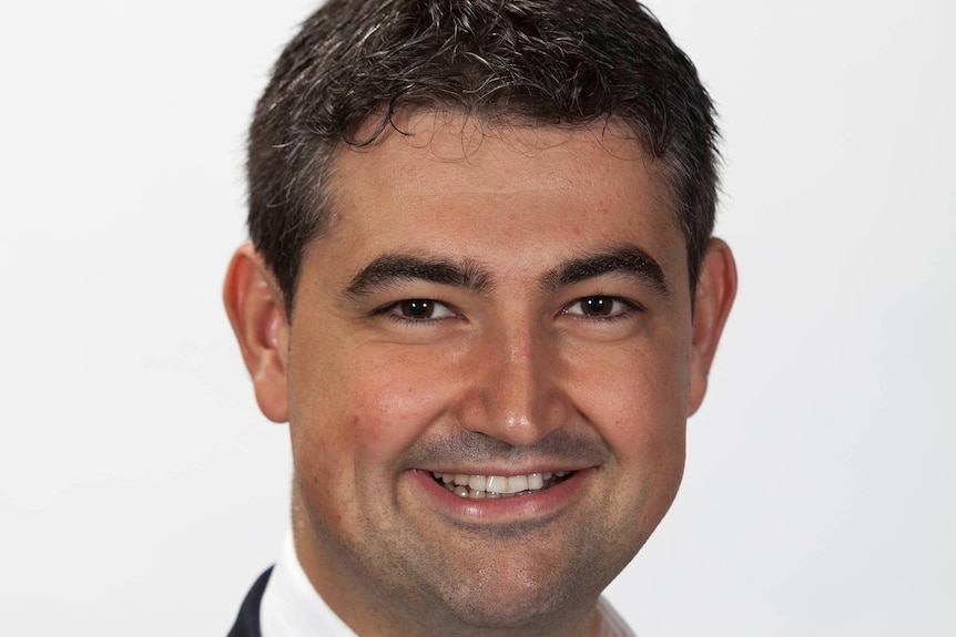 Head shot of a smiling man with black hair.  