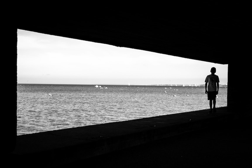 A generic black-and-white image of a boy looking out to the ocean.