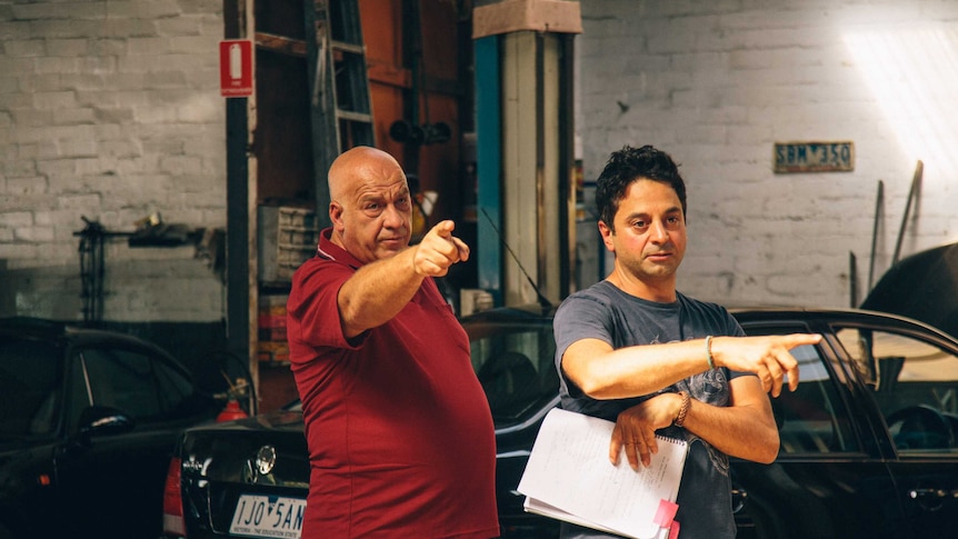 A male director working with a male actor on a film set.