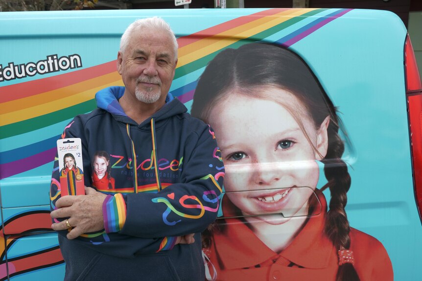 A man standing in front of van with his late daughter's picture on it.