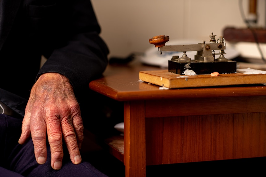 A hand sits limp next to a telegraph.