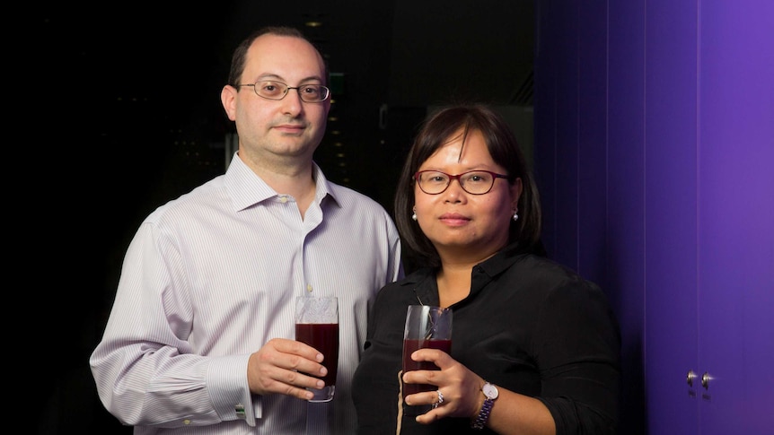 Dr Aaron Sverdlov and Dr Doan Ngo stand in a corridor holding glasses of beetroot juice.