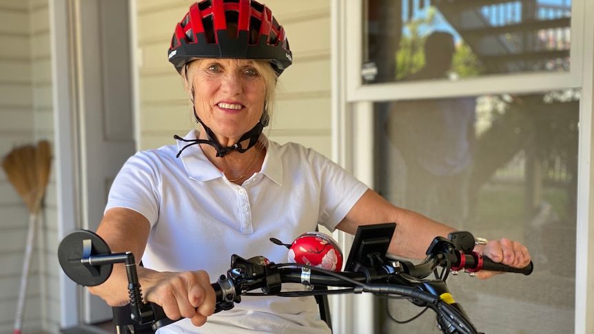 Woman wearing bike helmet sits astride her e-bike