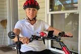 Woman wearing bike helmet sits astride her e-bike
