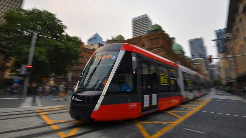 A train drives through a busy street at dusk