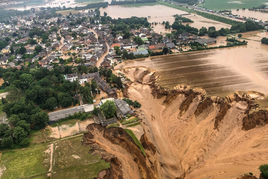 Vista dell'area che mostra le case circondate da acqua torrenziale e un pozzo nero. 