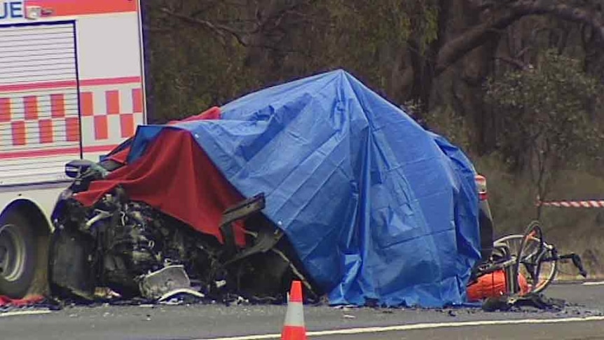 A badly damaged car on the Midland Highway between Bendigo and Elmore, covered by a blue sheet.