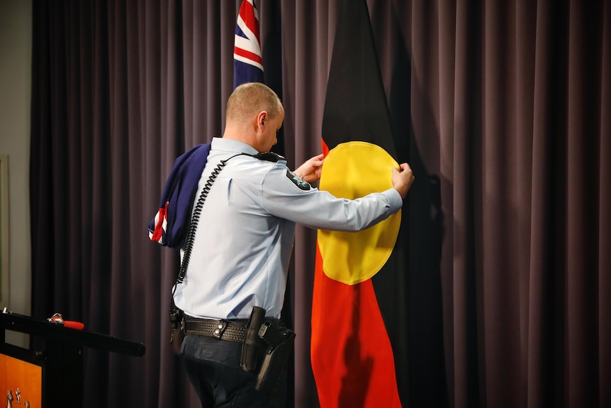 A security guard installs an aboriginal flag inside parliament house