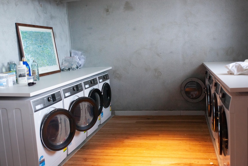 Eight washing machines in a laundry.