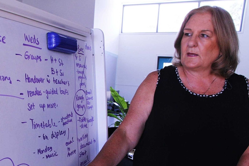 A woman stands at a whiteboard pointing to text about keeping doors open.