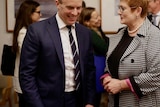 Dominic Raab and Marise Payne talk across a table surrounded by staffers and media.