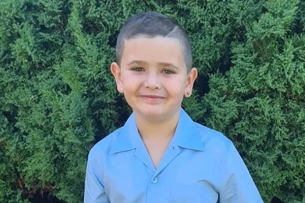 A young boy wearing a blue school uniform.